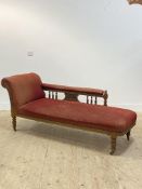 A Victorian oak framed chaise longue, upholstered in red chenille, with a moulded and carved show