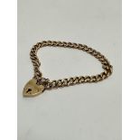 A 9ct gold curb link bracelet with heart shaped padlock and safety chain, (D x 8cm) 17.4g