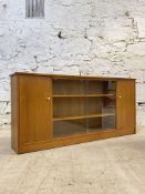 A mid century teak bookcase, with twin glazed sliding doors enclosing two adjustable shelves,