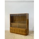 An Art Deco period walnut bookcase, the twin sliding glass doors enclosing two adjustable shelves (