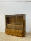 An Art Deco period walnut bookcase, the twin sliding glass doors enclosing two adjustable shelves (