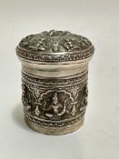 A Eastern white metal chased cylindrical container with domed top depicting various images of