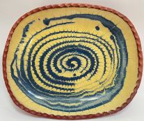 A large Wetheriggs Pottery earthenware dish with yellow/blue slipware swirl decoration to interior