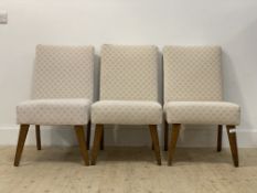 A set of three mid 20th century dining chairs, with upholstered back and seat, raised on square