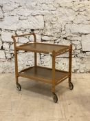 A mid century teak and laminate two tier drinks trolley moving on castors. H75cm, 69cm x 46cm