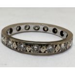 A white metal and yellow metal eternity style ring set sixteen diamond points, one stone damaged, in