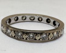 A white metal and yellow metal eternity style ring set sixteen diamond points, one stone damaged, in