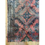 An old hand knotted Turkey runner rug, the red ground with stylised floral motifs and bordered (