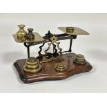 Edwardian brass set of postal scales with a collection of various brass weights on shaped mahogany