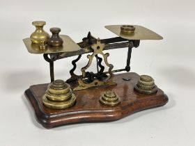 Edwardian brass set of postal scales with a collection of various brass weights on shaped mahogany