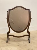 A Georgian style vanity mirror, the shield form mirror swivelling between scrolled uprights,