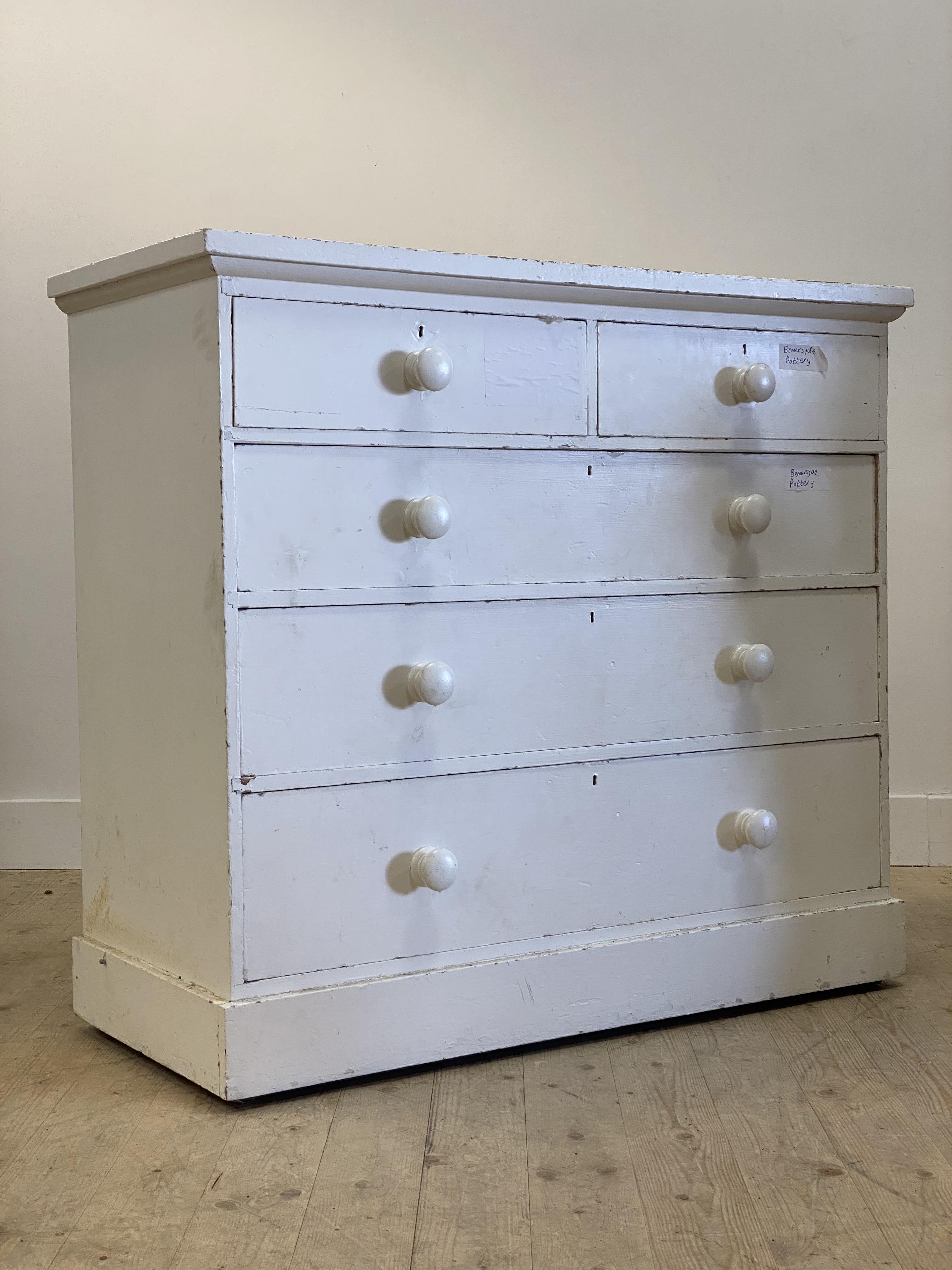 A 19th century white painted pine chest fitted with two short and three long drawers, on a plinth