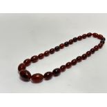 A dark brown graduated Amber bead necklace with screw fastening, (L x 20cm) 33.9g