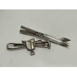 A 800 standard white metal pair of Skis brooch, (L x 8cm) and a silver saddle and whip brooch, (L