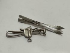 A 800 standard white metal pair of Skis brooch, (L x 8cm) and a silver saddle and whip brooch, (L