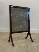 An early 20th century mahogany fire screen, with embroidered panel worked in a floral design, on