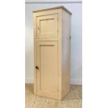 A cream painted pine two part cabinet, late 19th century, with panelled door enclosing void