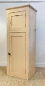 A cream painted pine two part cabinet, late 19th century, with panelled door enclosing void