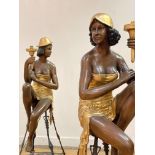 An opposing pair of cast parcel gilt and bronzed metal figural uplighters in the Art Deco style,