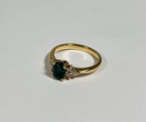 An emerald and diamond cluster ring, the oval-cut emerald claw-set between twin groups of three