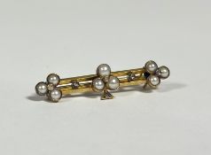 A seed pearl and diamond bar brooch, c. 1900, set to the centre with a three leaf clover design