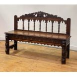 A late Victorian oak hall bench of 18th century design, the green man and acanthus carved pediment