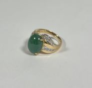 A jade and diamond dress ring, the oval jade cabochon claw-set between crossover shoulders each