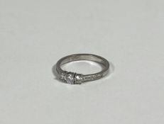 A three-stone diamond ring, the three graduated round brilliant-cut stones claw-set on a palladium