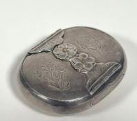 A white metal vesta case, c. 1900, probably Japanese, of shaped oval form, the cover with mixed