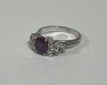 A ruby and diamond cluster ring, the oval-cut ruby weighing c. 1ct, claw-set between twin groups