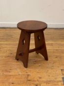 An Arts and Crafts period walnut lamp table, the circular top raised on pierce carved and splayed