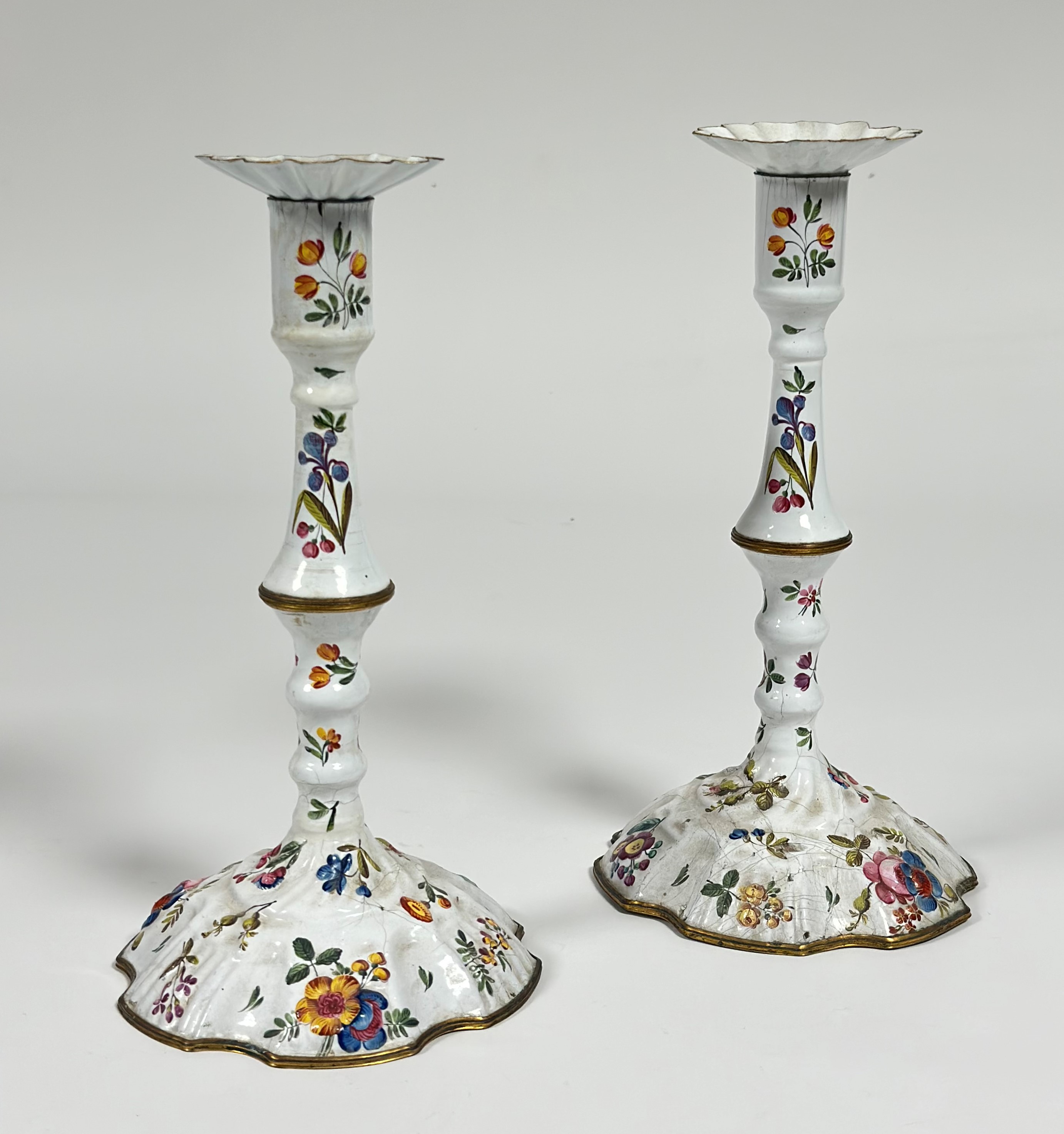 A pair of Staffordshire painted enamel candlesticks, last quarter of the 18th century, in two