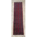 A Turkoman bokhara type runner rug, hand knotted, the red ground with two rows of guls, within a