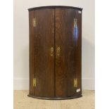 A George III oak bow front wall hanging corner cupboard, two doors enclosing an interior fitted with