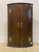 A George III oak bow front wall hanging corner cupboard, two doors enclosing an interior fitted with