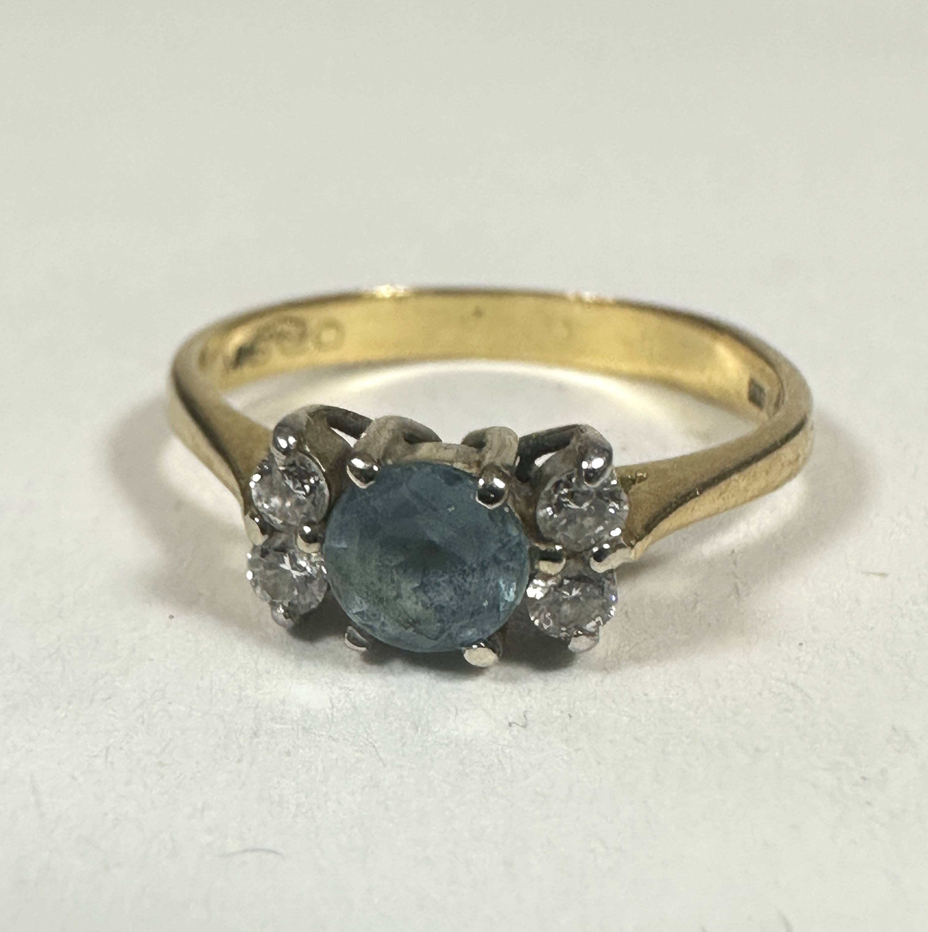 A 18ct gold Aquamarine ring, the circular stone approximately 0.33ct flanled by tow clear stones, K.