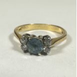 A 18ct gold Aquamarine ring, the circular stone approximately 0.33ct flanled by tow clear stones, K.