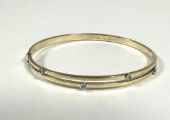 A 9ct gold twin bar stiff hinged bangle set four paste set stones, (D x 6cm) show no signs of damage