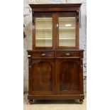 A Victorian mahogany bookcase on cupboard, the projecting cornice over two glazed doors enclosing