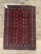 A hand knotted Pakistani Bokhara type rug, the red field with two rows of guls and bordered 133cm