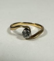 A 18ct gold solitaire Diamond ring in rubover setting on cross over band, 0.20ct approximately, H.