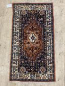 A Persian hand knotted rug, the dark field with geometric and stylised foliate design, within an