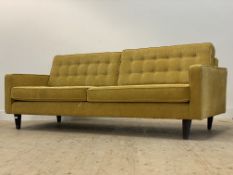 A large contemporary sofa, upholstered in yellow chenille type fabric, raised on ebonised square
