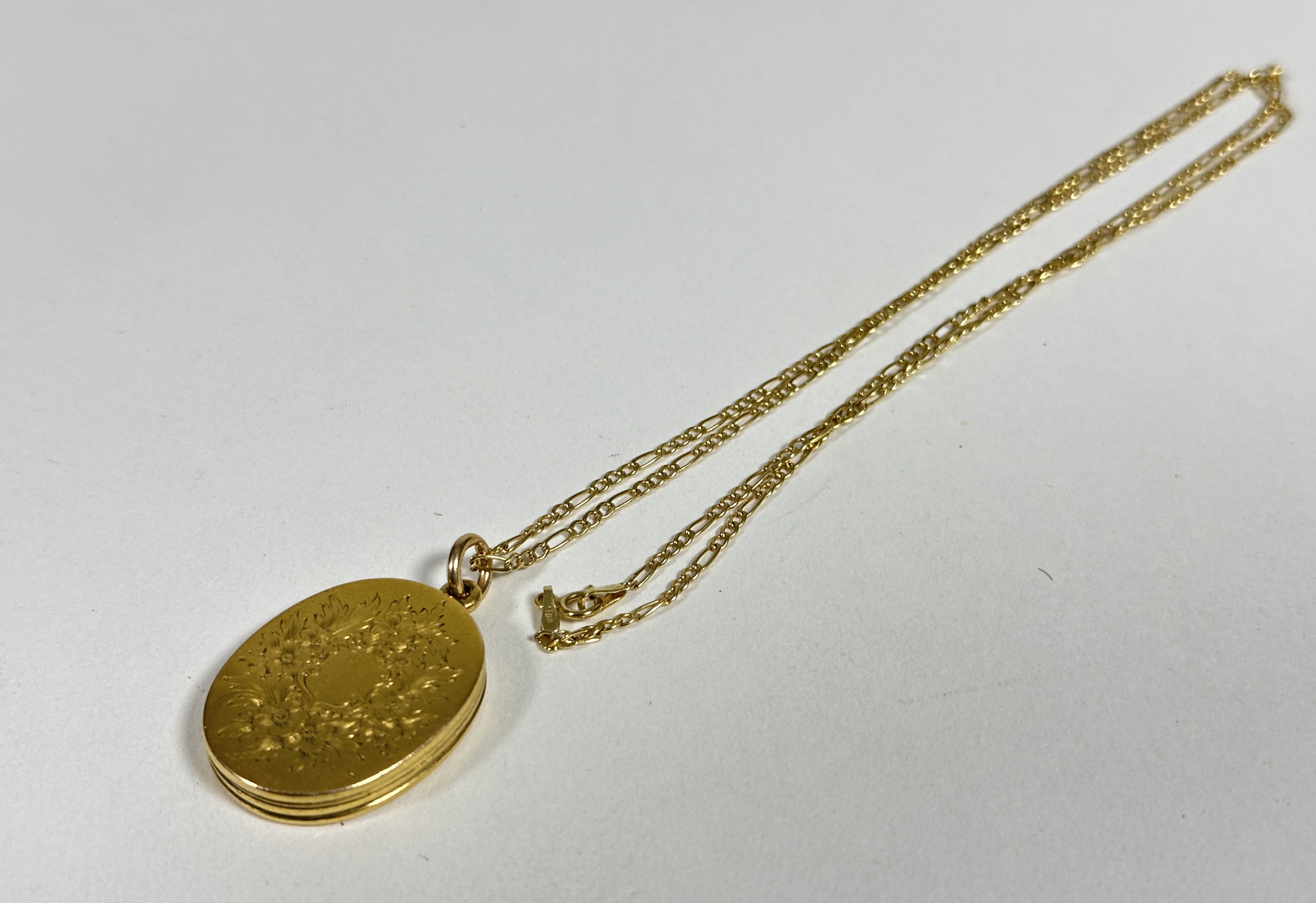 A late 19thc yellow metal oval engraved locket, opening to reveal two Victorian photographs, (L x