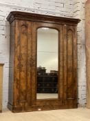 A well figured Victorian walnut wardrbe, the projecting cornice above a centre mirrored door,