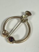 A late 19thc / early 20thc gilt metal Penanular style plain brooch with thistle bi-coloured glass on