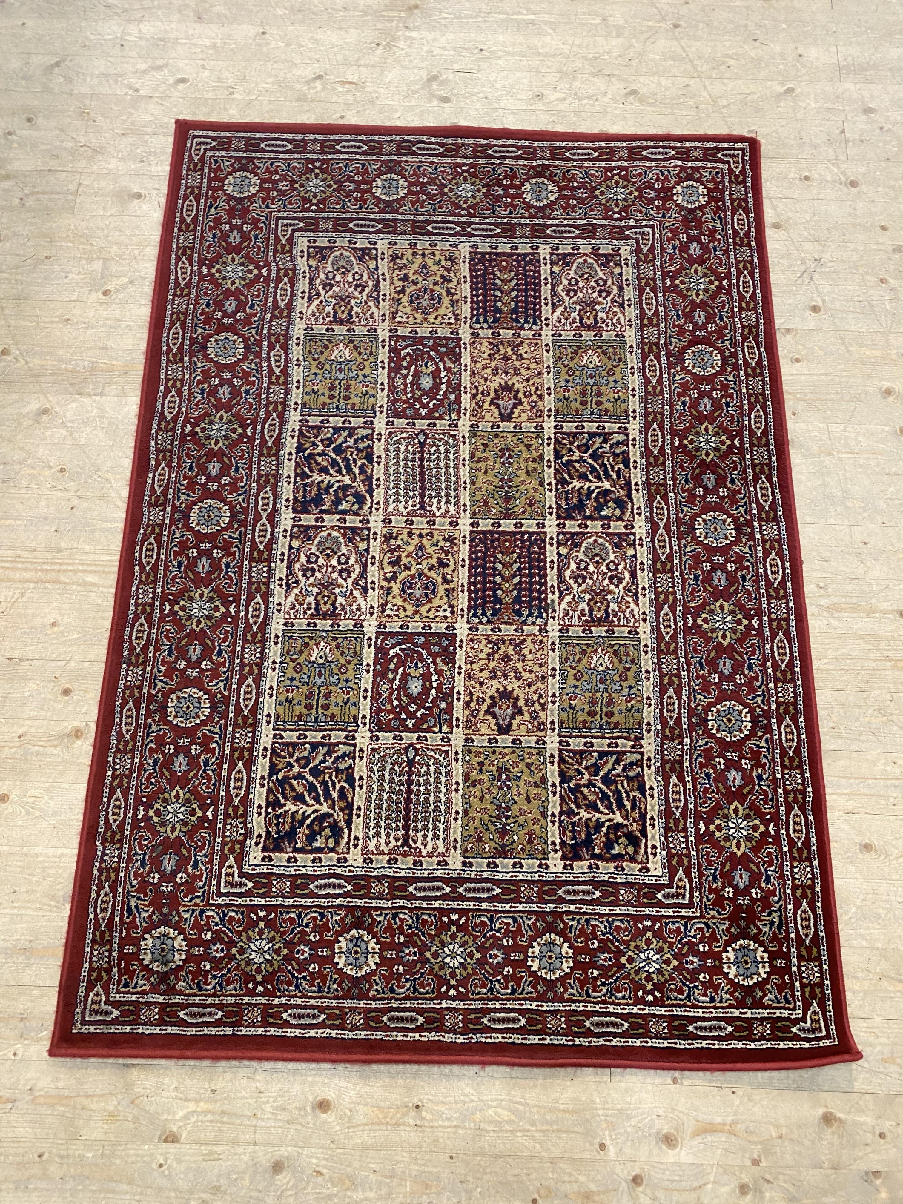 A Persian style garden rug, the red ground decorated with garden motifs within a guarded border