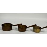 A set of three graduated brass sauce pans with iron handles, D x 17.5cm , 15cm , 13cm,) (3)