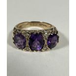 A 9ct Gold graduated three stone Amethyst and Diamond ring, the oval centre stone set with four
