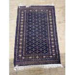 A hand knotted Turkoman style rug, the blue field with lozenge motif within a deep border 125cm x